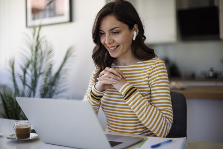 Young smiling woman with bluetooth headphones having video call at home