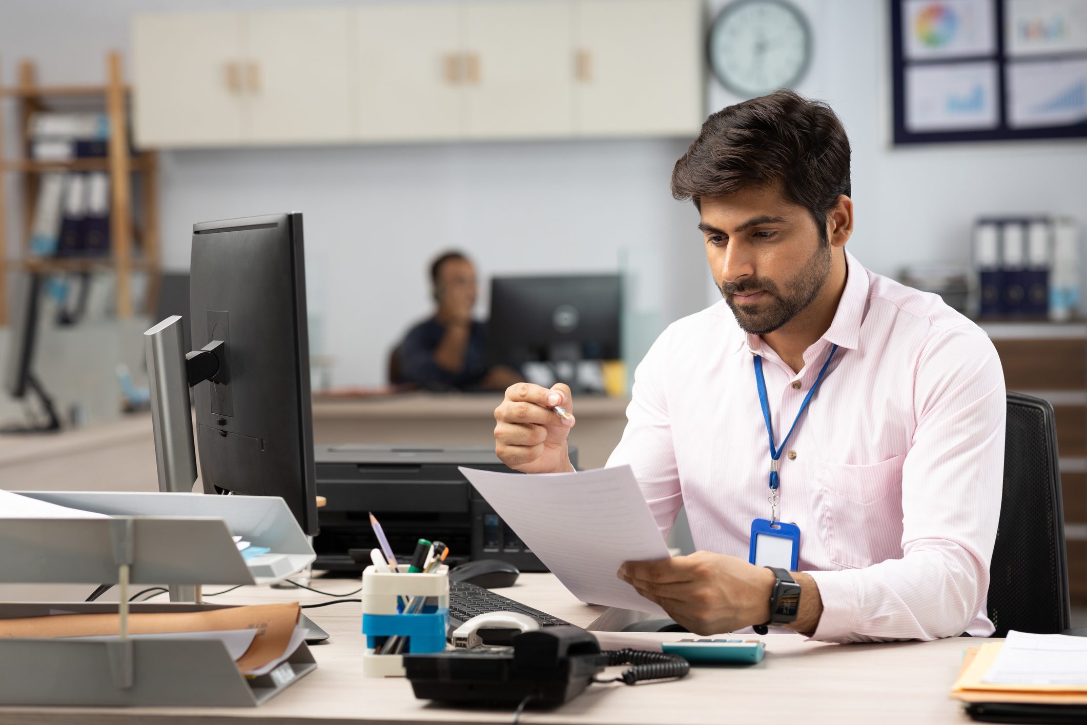 Businessman with Computer Reading Documents in Office stock photo