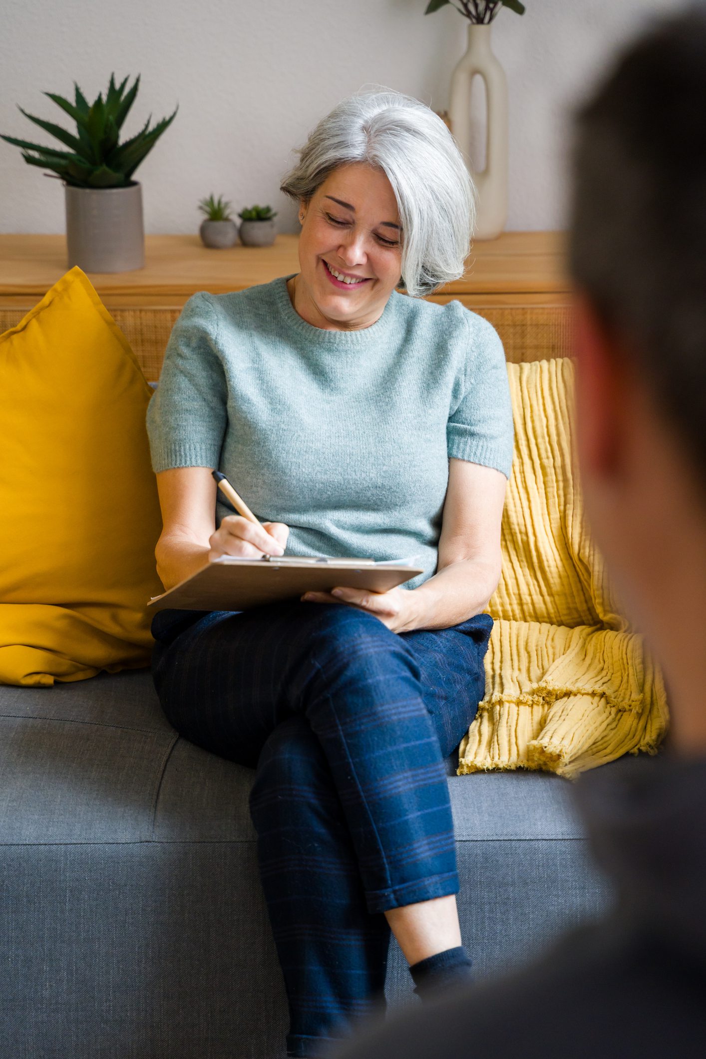 A female counselor smiles during a session with an unrecognizable woman.