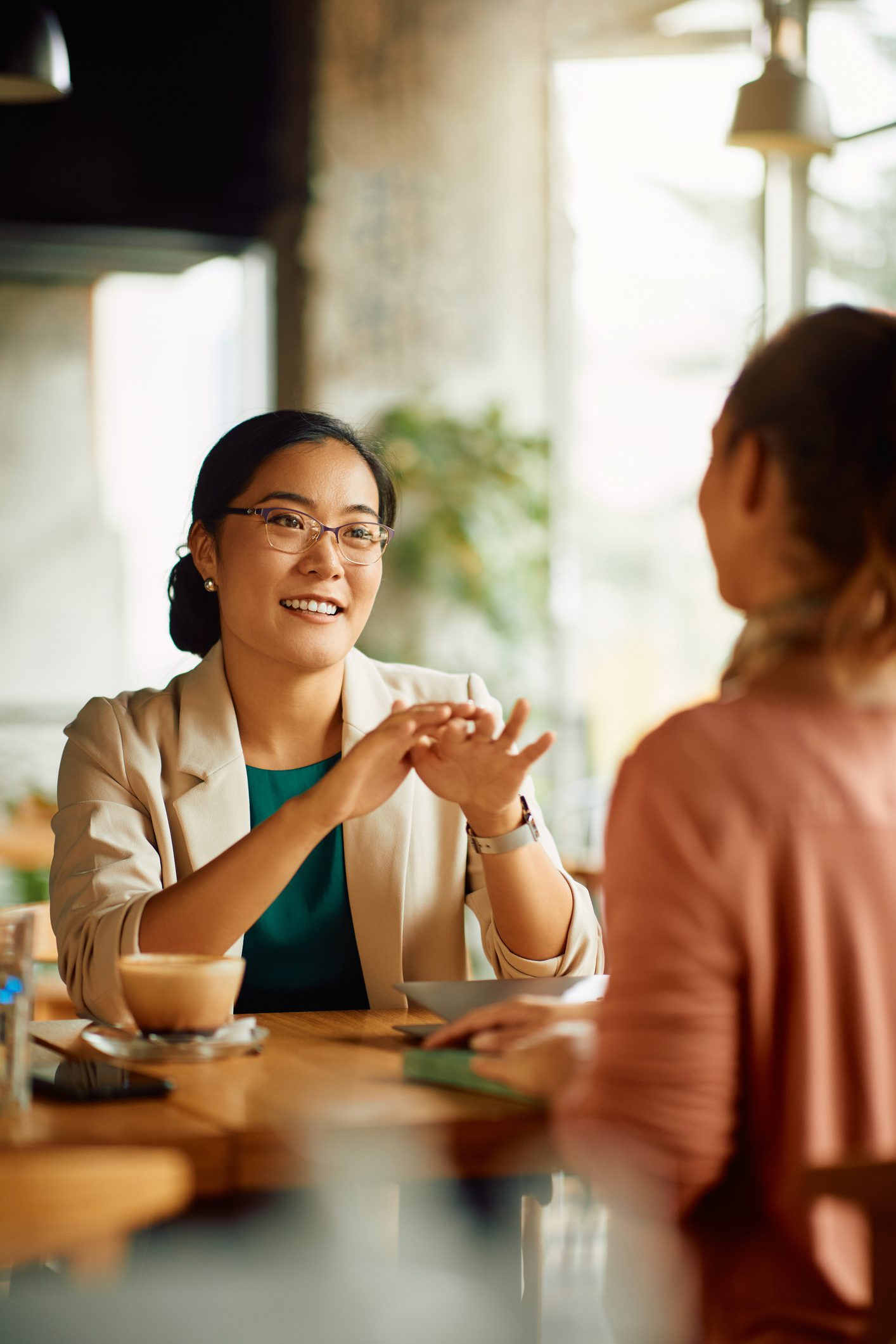 female psychiatrist writing in clipboard and talking to smiling man gesturing by hands in office